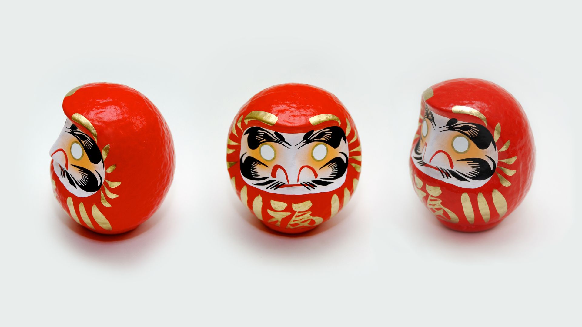金の装飾と「福」の文字が入った赤いだるま3体