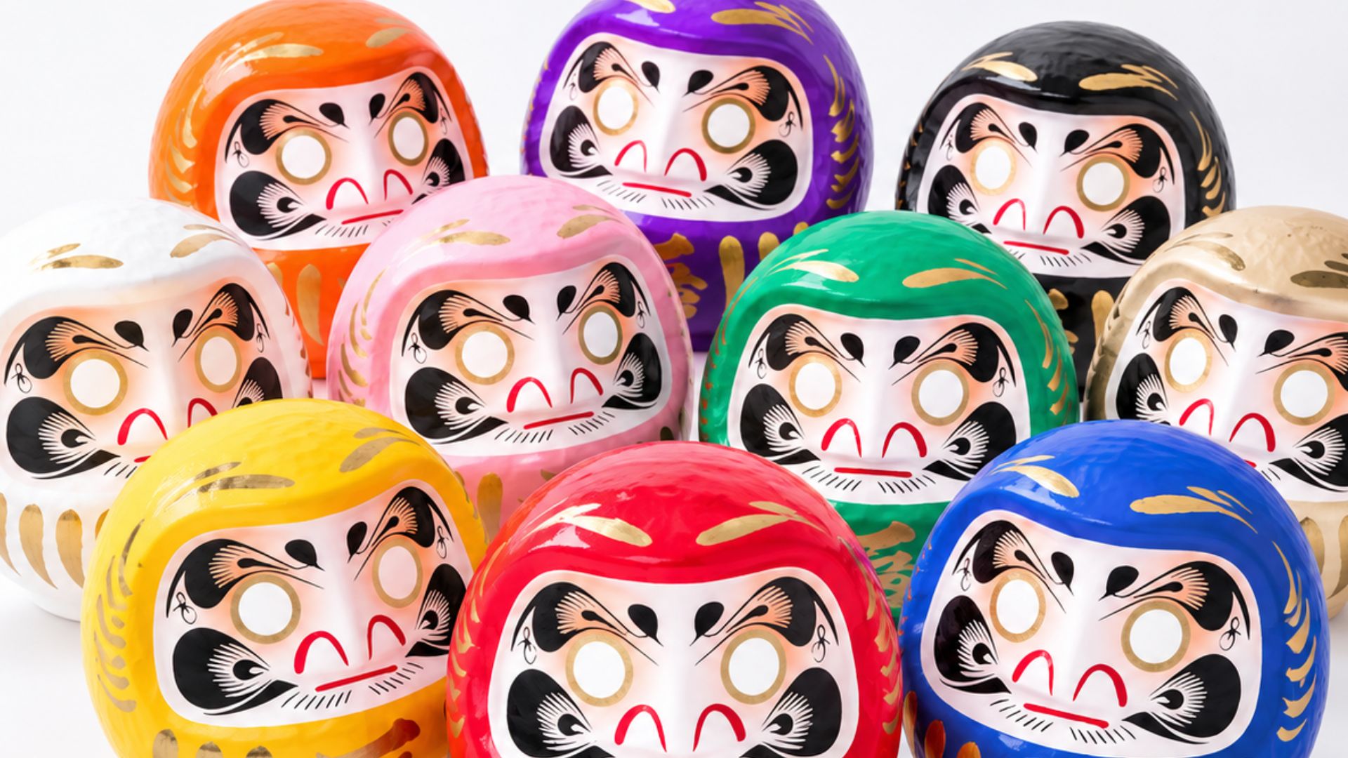 オレンジ、紫、黒、白、ピンク、緑、金、黄、赤、青——色とりどりのだるま